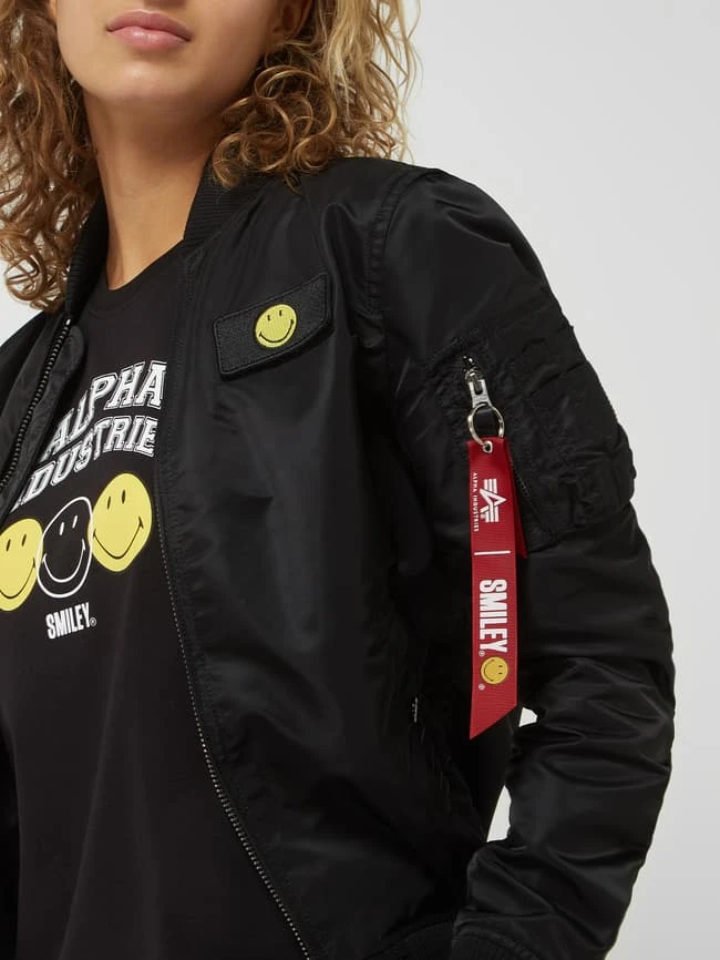 Alpha Industries Bomber Mit Ärmeltasche - Alpha Industries-Smiley® X P&C – Exklusiv Bei Uns - Schwarz 3 Alpha Industries Bomber Mit Ärmeltasche - Alpha Industries-Smiley® X P&C – Exklusiv Bei Uns - Schwarz – Bild 3